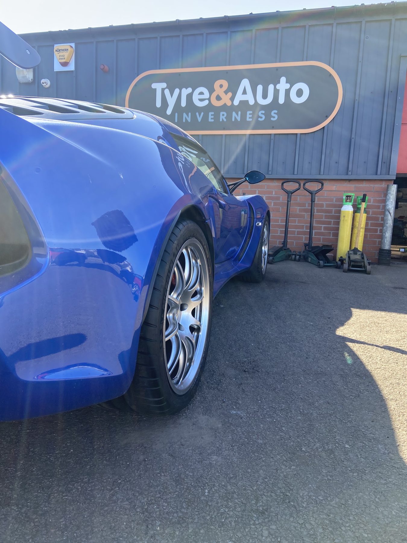 A blue sports car in front of the Tyre&Auto Inverness sign