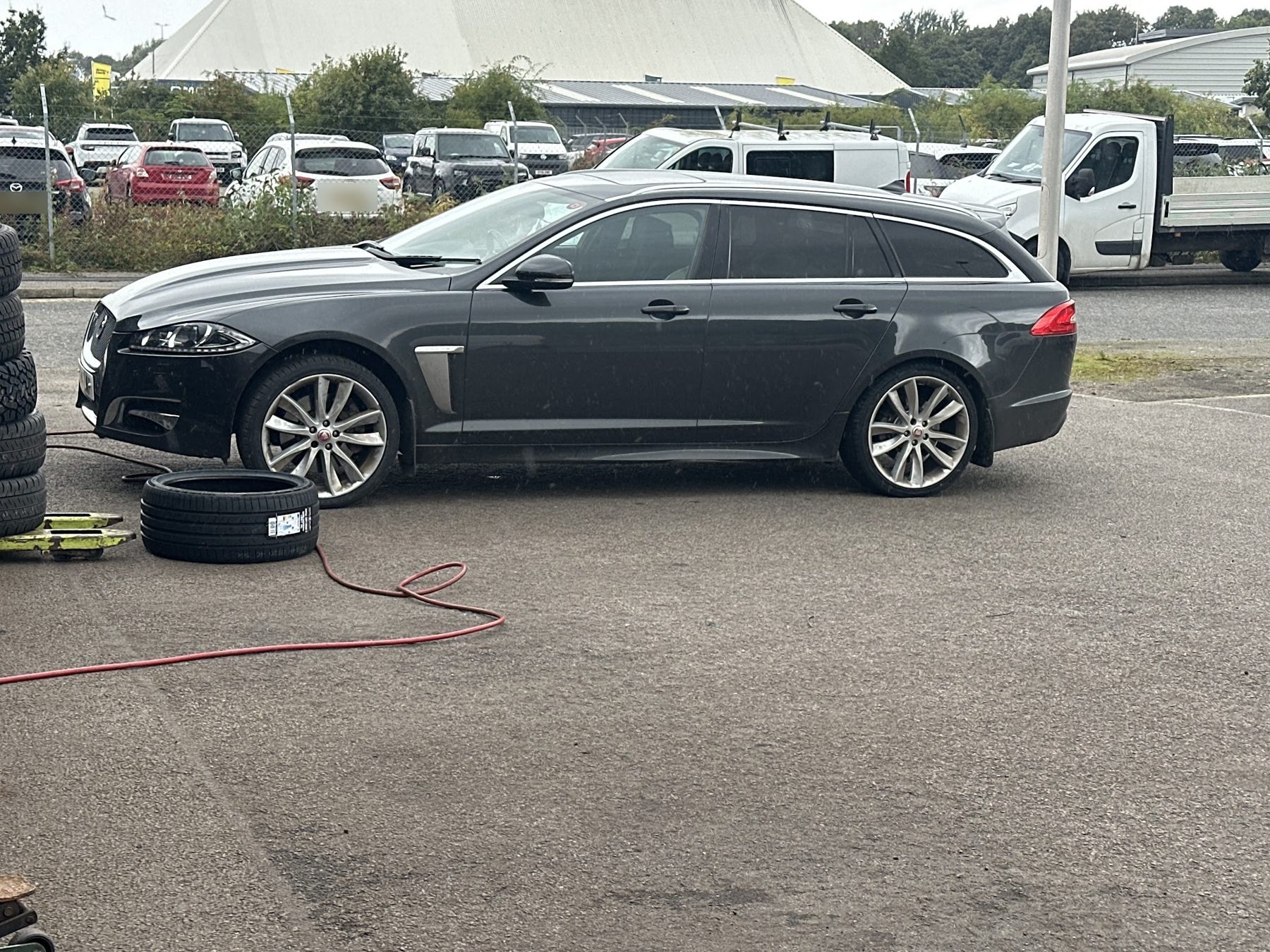 A Jaguar estate in the yard with new tyres stacked beside it
