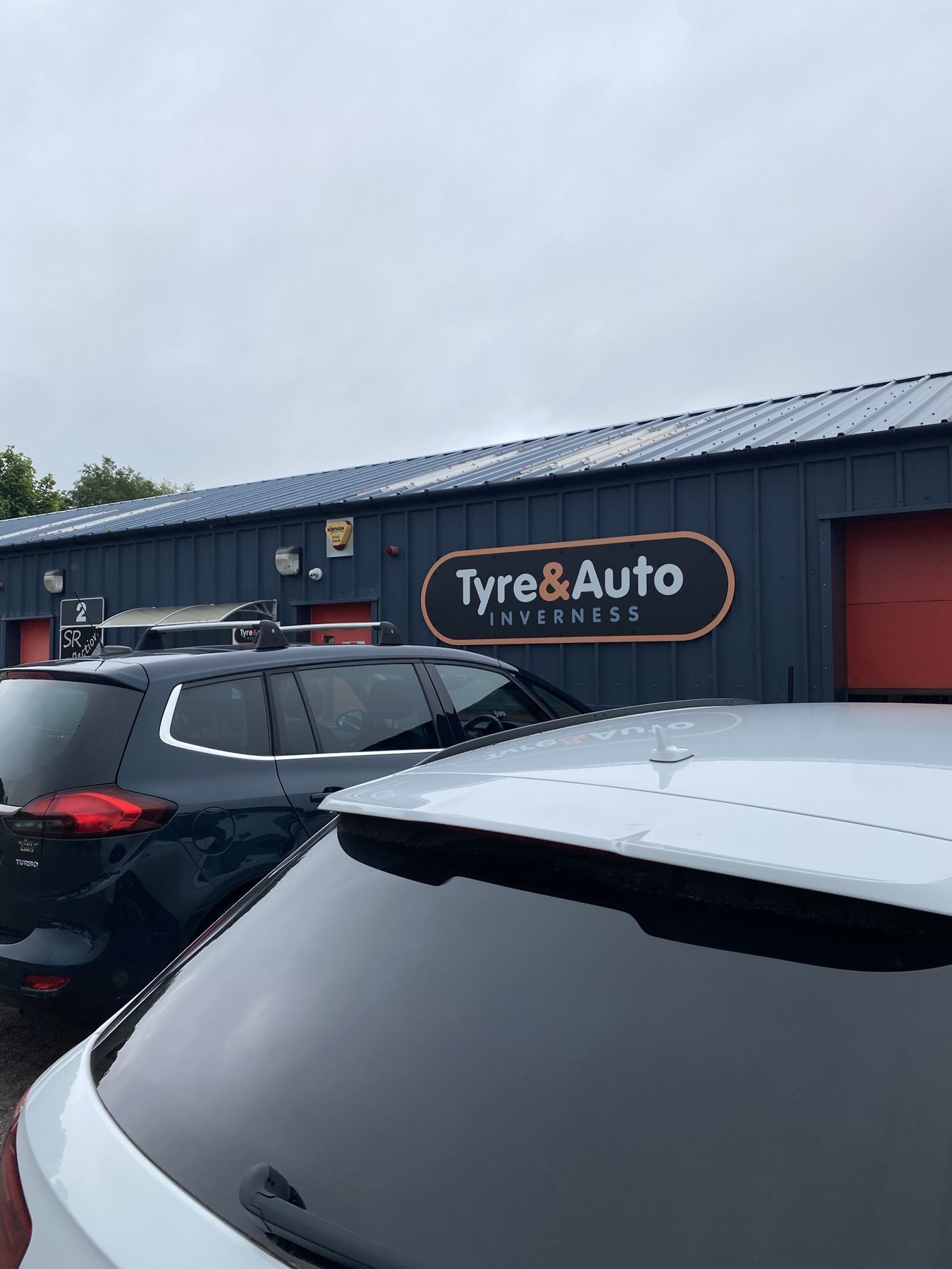 A car in the yard with the workshop behind