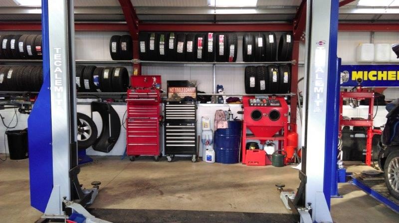 A two-post vehicle lift and toolboxes inside the workshop